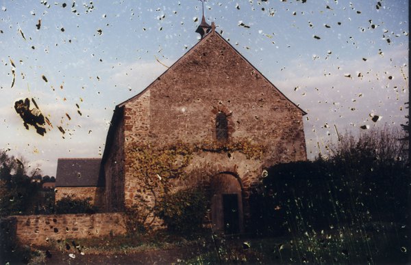 Chapelle en pierre au milieu de la campagne. Image abîmée.