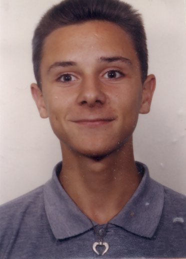Visage de jeune homme brun  souriant en polo bleu.