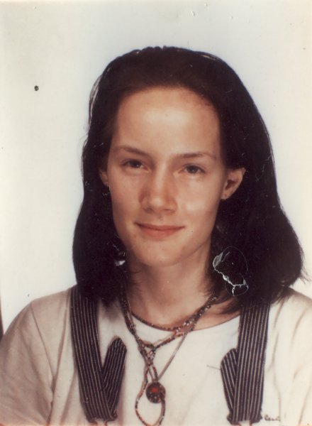 Visage de femme brune de face à collier à lanière.