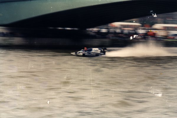 Bateau de course passant sous un pont, éclaboussures d'eau.ᴬᴵ