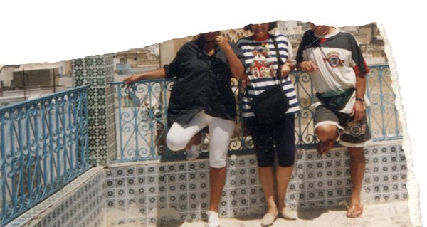 Trois personnes prennent la pose devant une balustrade. Fragment.