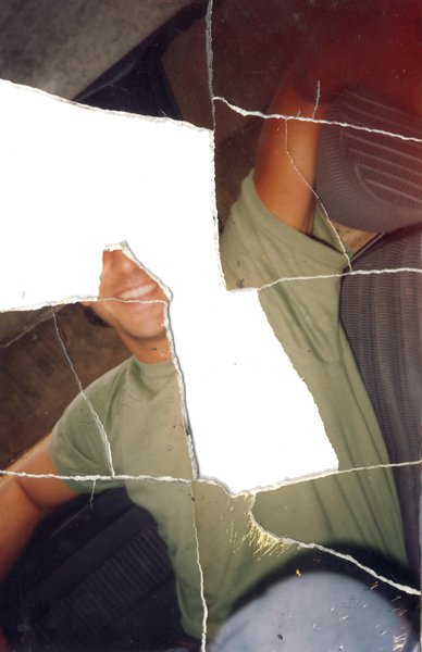 Homme brun souriant en tee-shirt vert. Image déchirée en partie reconstituée.