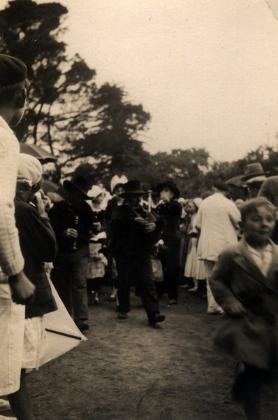 Foule en tenue traditionnelle et chapeaux lors d'une fête en extérieur. Noir et blanc.ᴬᴵ