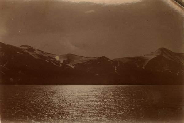 Chaîne de montagnes reflétée sur un lac au soleil couchant. Noir et blanc.ᴬᴵ