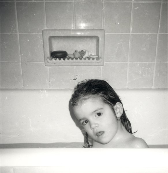 Petite fille brune épaule nue dans une baignoire.