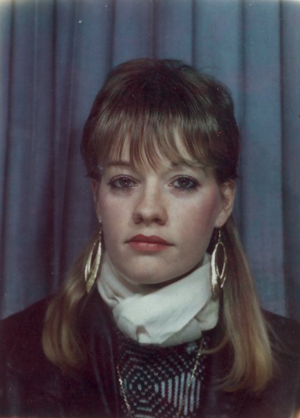 Portrait d'une jeune femme avec boucles d'oreilles et foulard blanc devant un rideau bleu.ᴬᴵ