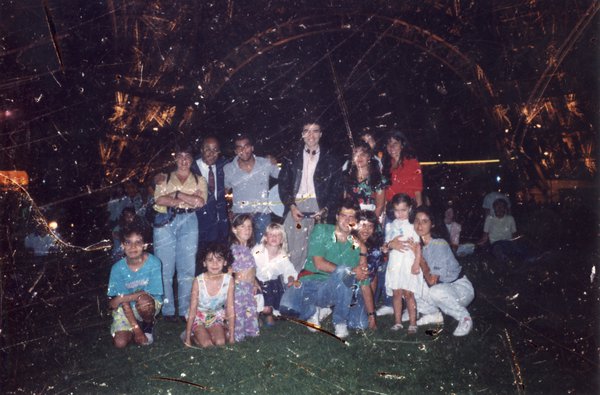 Hommes, femmes, et enfants posant en plein air. Image abîmée.