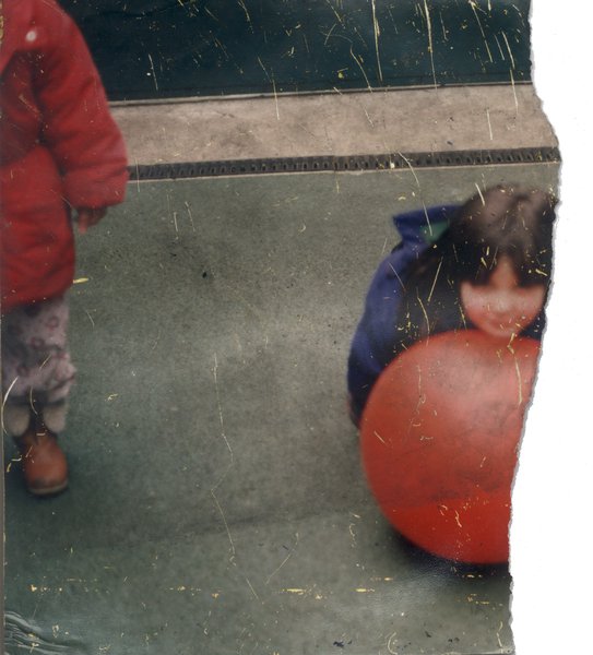Deux enfants dehors, l'un en manteau rouge, l'autre avec un ballon rouge. Fragment déchiré.ᴬᴵ