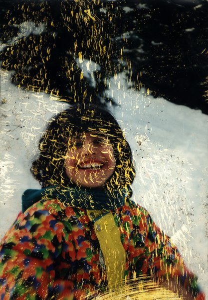 Personne souriante en manteau multicolore et écharpe devant la neige. Fragment très abîmé.ᴬᴵ