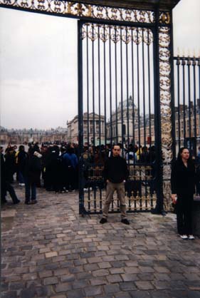 Grille de la cour  pavée du château de Versailles et touristes.