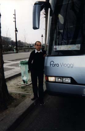 Homme debout près d’un autocar touristique dans la rue.