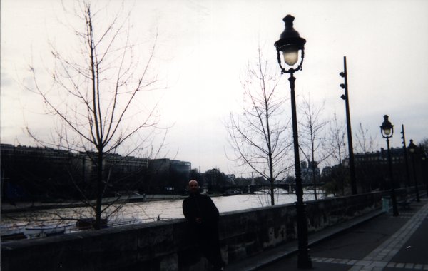 Homme les coudes posés sur le parapet d’un quai au-dessus de la Seine à Paris.