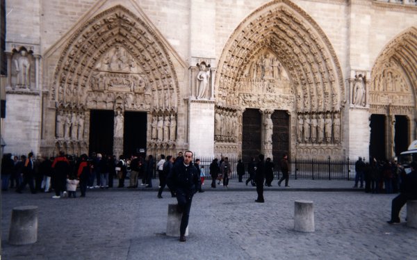 Homme debout devant le tympan de la cathédrale Notre-Dame de Paris.