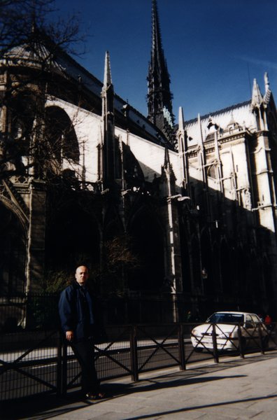 Homme accoudé à une balustrade devant la cathédrale Notre Dame de Paris.