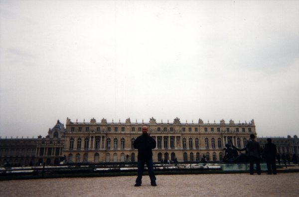 Homme devant un bassin du parc du Château de Versailles.