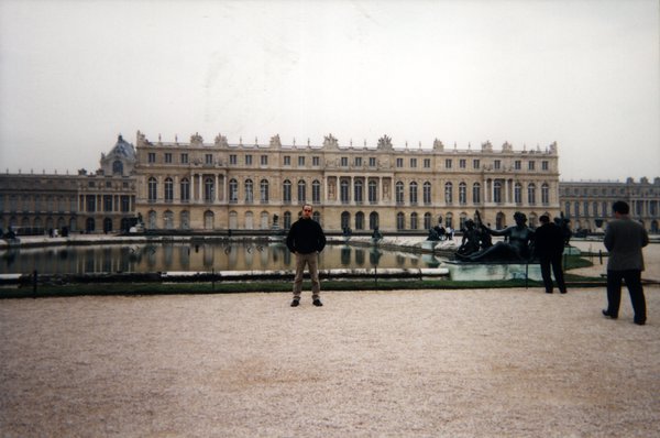 Homme devant un bassin du parc du Château de Versailles.