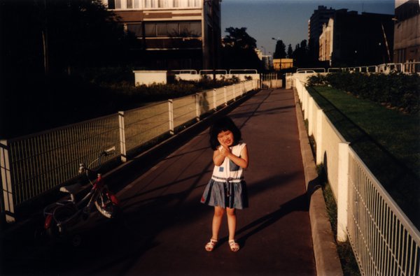 Petite fille debout près de son vélo sur une passerelle.