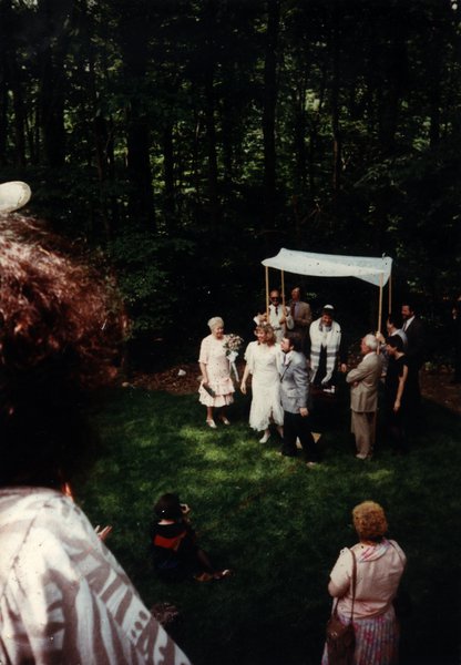Mariage juif avec dais nuptial et convives dans un jardin.