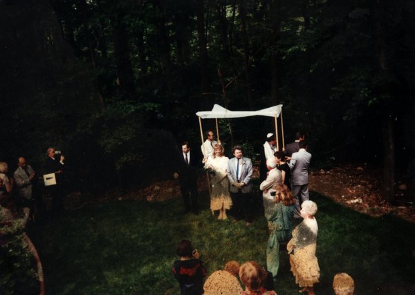 Mariage juif avec dais nuptial et convives dans un jardin.