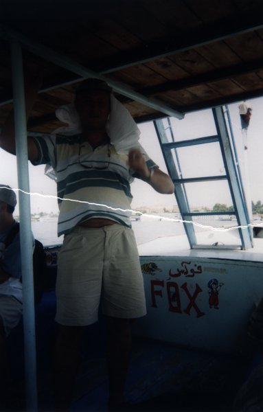 Homme debout en short et polo sur un bateau.