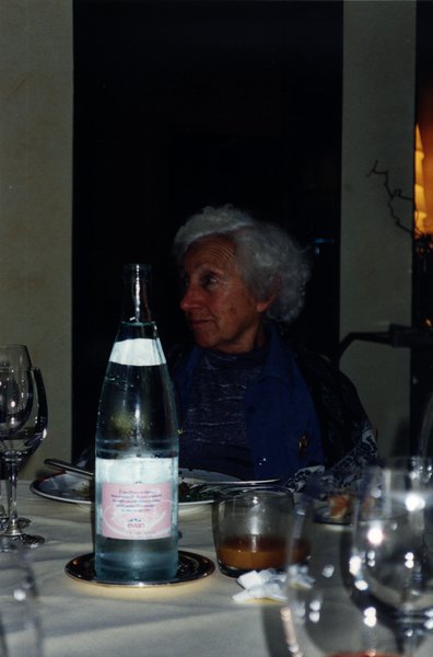 Femme âgée assise à une table devant les restes d’un repas.