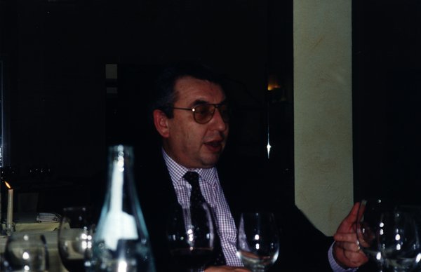 Homme à lunette assis à une table devant les restes d’un repas.