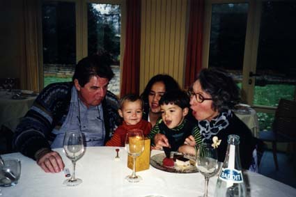 Homme, femme, et enfants soufflent des bougies devant un goûter d’anniversaire.