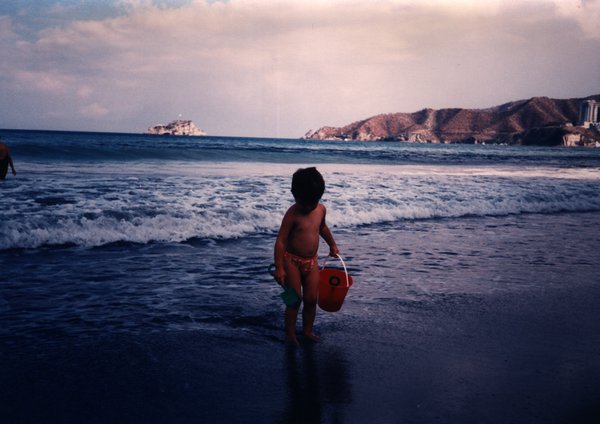 Enfant avec une pelle et un seau au bord de la mer.