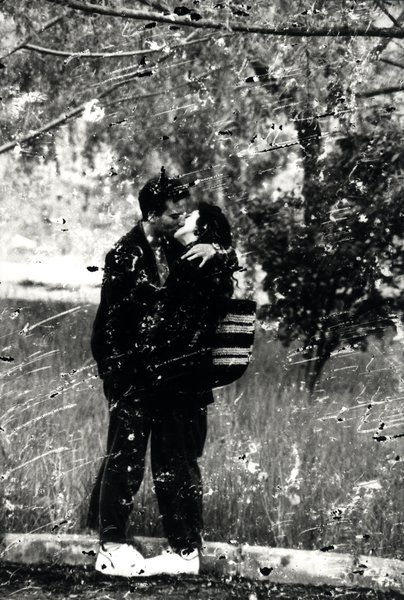 Couple s'embrassant sous un arbre. Image très abîmée. Noir et blanc.ᴬᴵ