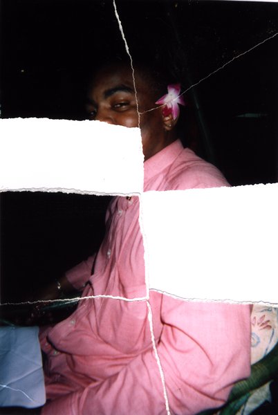 Personne en tenue rose avec une fleur à l'oreille dans une voiture. Image avec déchirure, reconstituée.ᴬᴵ