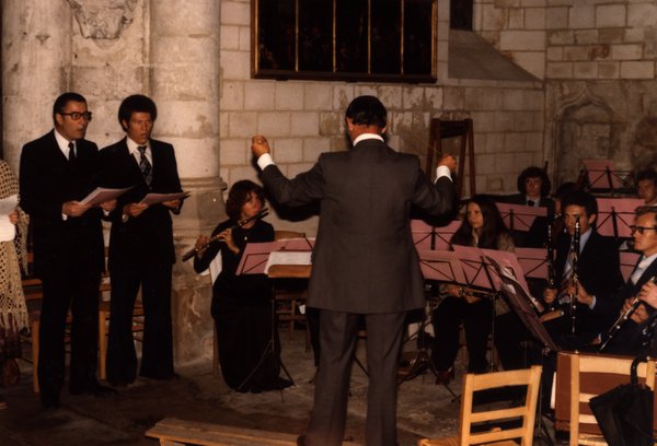 Deux chanteurs avec partitions et chef d'orchestre dirigeant un ensemble dans une église.ᴬᴵ
