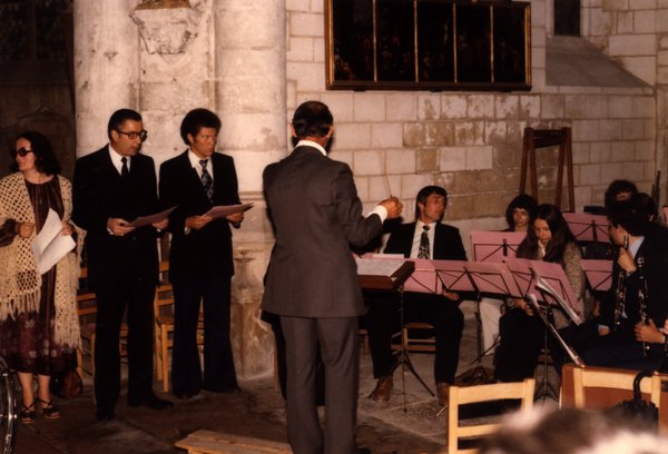Choristes debout avec partitions et chef d'orchestre dans une église en pierre.ᴬᴵ