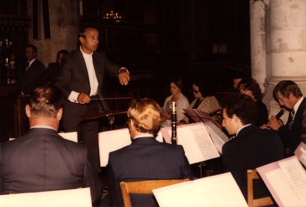 Chef d'orchestre dirigeant des clarinettistes assis dans une église.ᴬᴵ