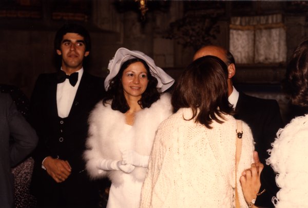 Mariée souriante entourée d'invités à l'intérieur.ᴬᴵ