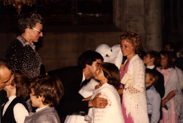 Marié embrassant une fillette sur la joue, entouré d'enfants et d'invités.ᴬᴵ