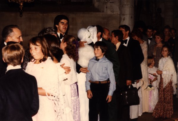 Groupe d'invités et d'enfants autour d'une personne portant un grand costume blanc.ᴬᴵ