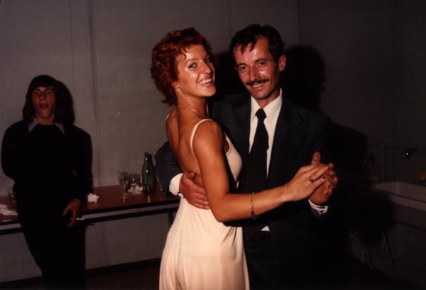 Femme rousse en robe crème dansant avec un homme moustachu en costume sombre.ᴬᴵ