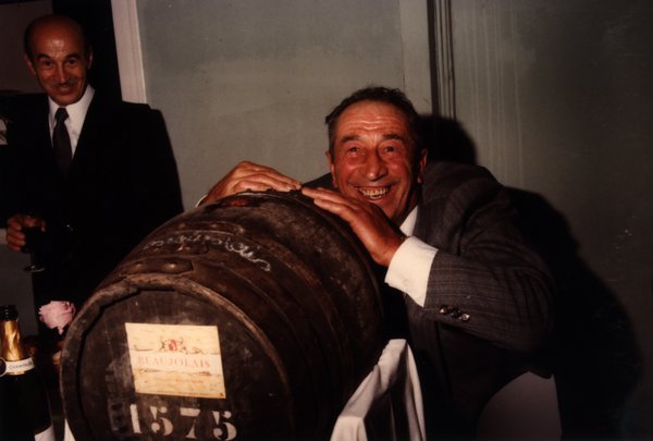 Homme enlaçant un tonneau de vin Beaujolais 1975.ᴬᴵ