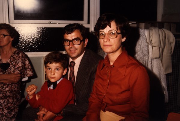 Portrait de famille près d'une fenêtre : un enfant, un homme et une femme à lunettes.ᴬᴵ