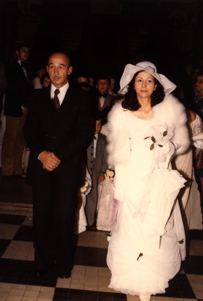 Mariée en robe blanche et homme en costume noir marchant sur un sol à damier.ᴬᴵ