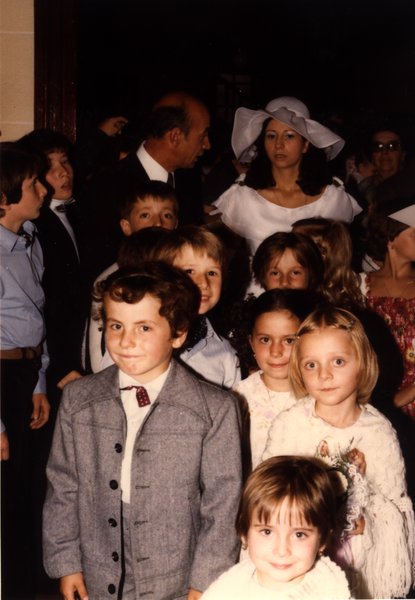 Groupe d'enfants avec la mariée en arrière-plan, devant une porte.ᴬᴵ