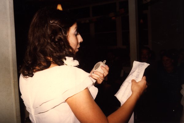Femme en robe blanche faisant un discours au micro.ᴬᴵ