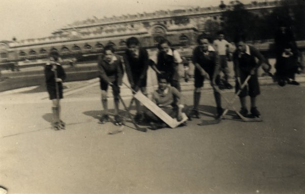 Équipe de hockey sur patins à roulettes avec un gardien de but assis au centre. Noir et blanc.ᴬᴵ