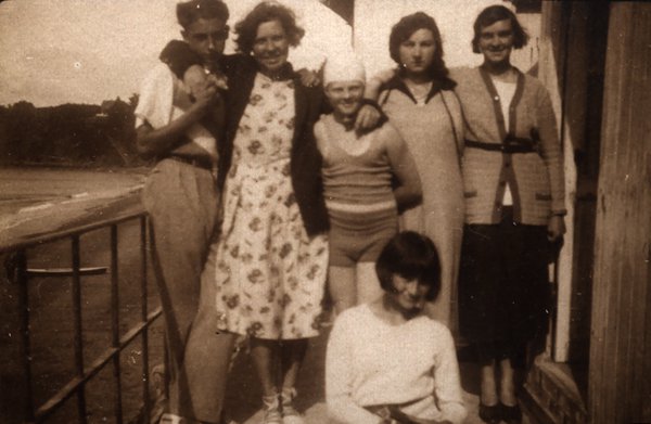 Groupe de jeunes gens sur une terrasse au bord de l'eau. Noir et blanc.ᴬᴵ