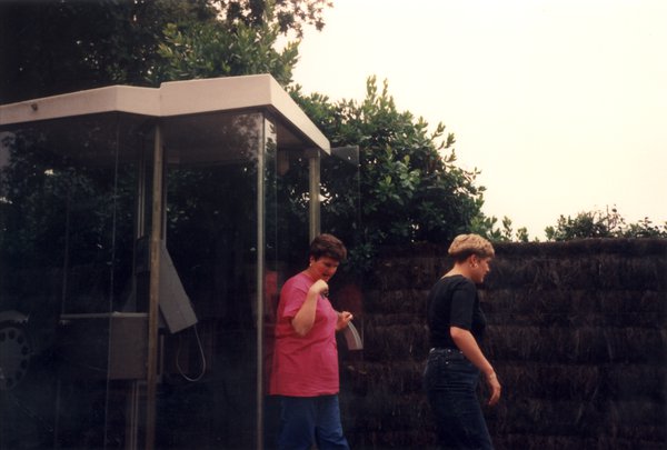 Deux femmes sortent d’une cabine téléphonique.