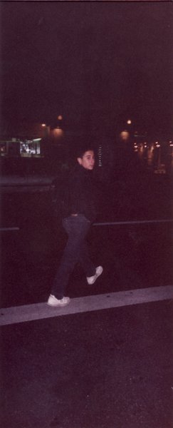 Jeune homme marche dans la rue, la nuit.