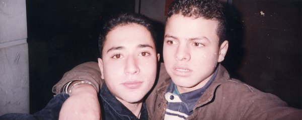 Visage de deux jeunes hommes enlacé.