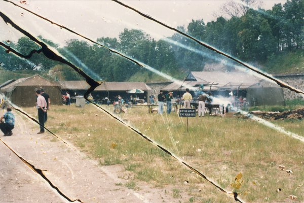 Tentes dressées dans la campagne et barbecues. Image abîmée.