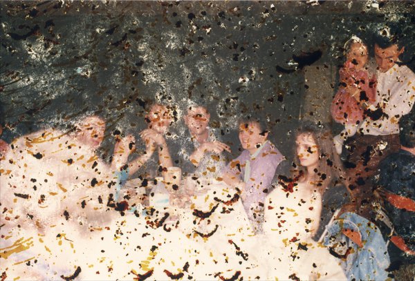 Hommes, femmes et enfants autour d’un repas. Image abîmée.