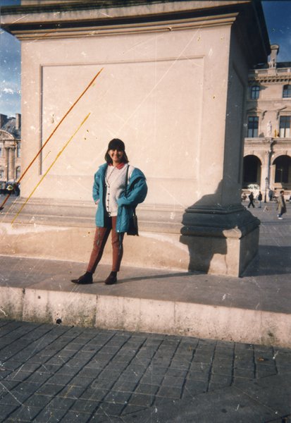 Jeune femme pose debout devant une statue.